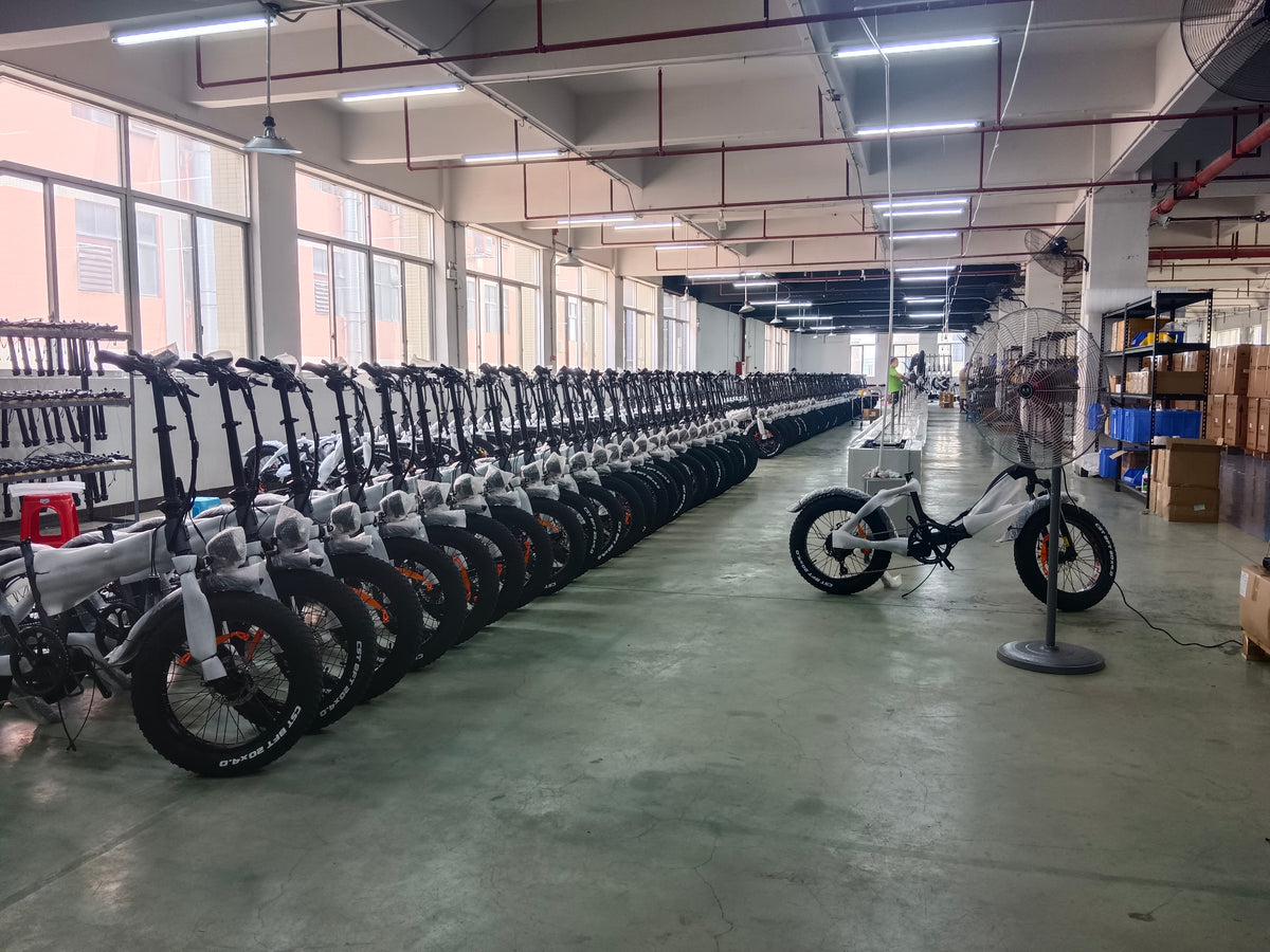 E-bikes arranged in rows beside workshop equipment